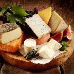 49117942 - gourmet cheese platter on a rustic buffet with a large assortment of tasty regional and speciality soft and semi-hard cheeses displayed with fresh grapes and figs, close up view